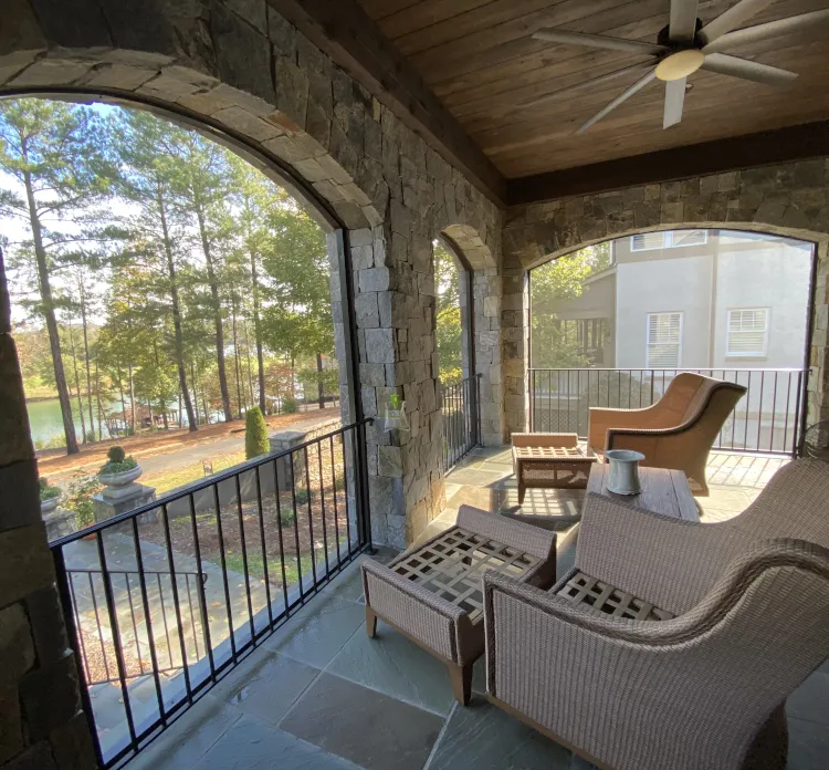 Luxury stone porch with retractable screens, overlooking a scenic outdoor landscape with comfortable seating